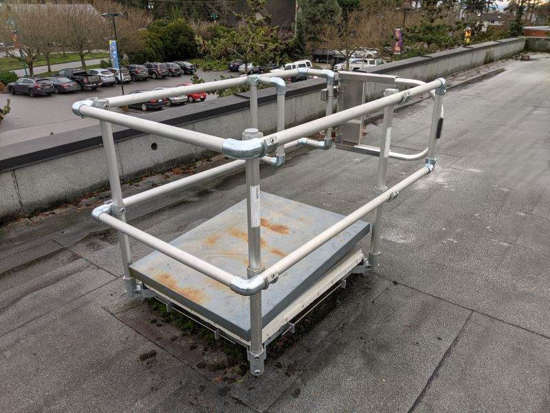 A metal platform with a safety railing on a rooftop